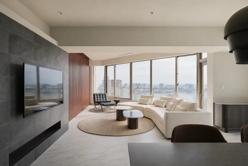 Modern living room with a curved white sectional, round coffee tables, and floor-to-ceiling city views. Note: ensure the most important details are captured: curved sofa, coffee tables, large windows, city view.