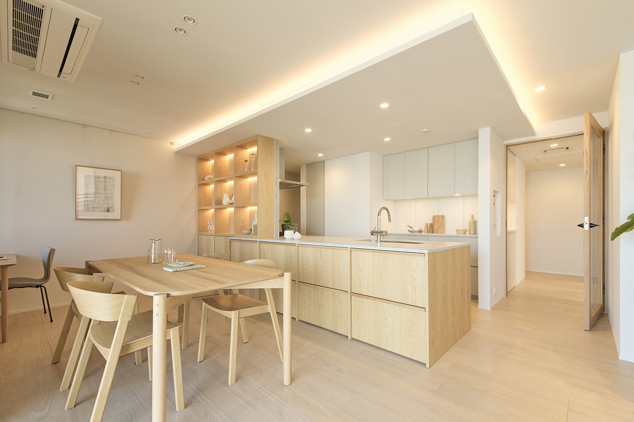 Bright open-plan kitchen and dining area with light wood furniture and built-in shelving.