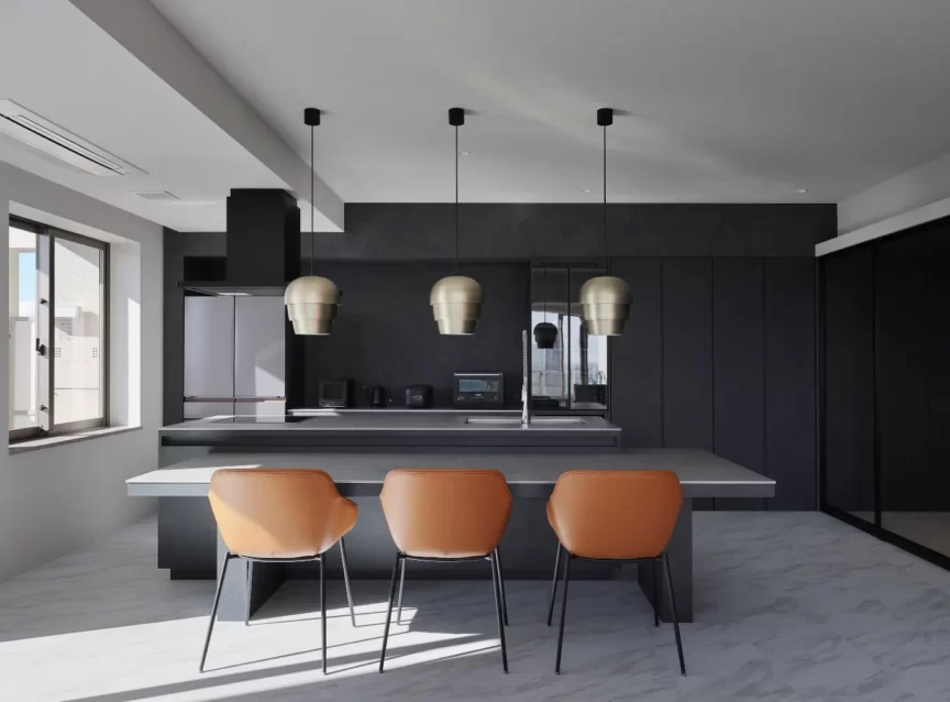 Modern black kitchen with an island, three copper pendant lights, and orange bar stools facing the counter.